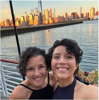 Carmela Unguez with one of her children by a waterfront skyline