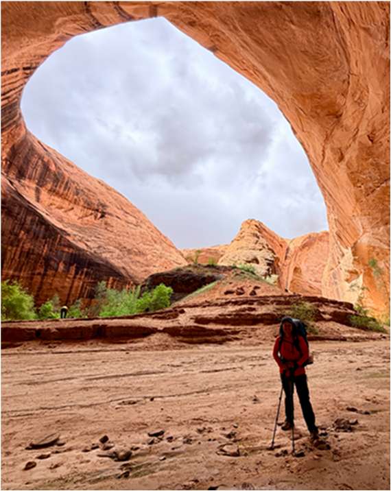 Carmela Unguez hiking beneath a red rock arch