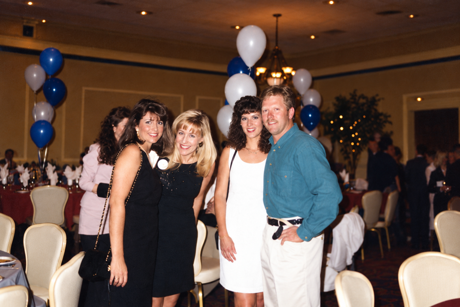 Three women and a man pose together. Color interpretation.