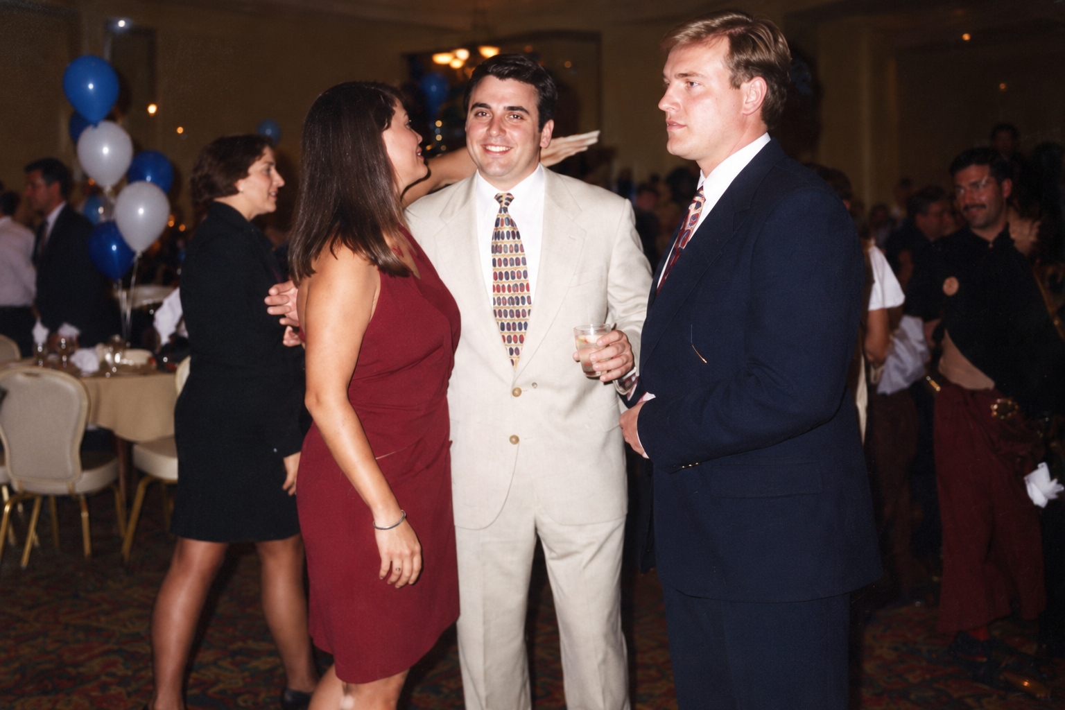 A woman and two men converse at the reunion. Color interpretation.
