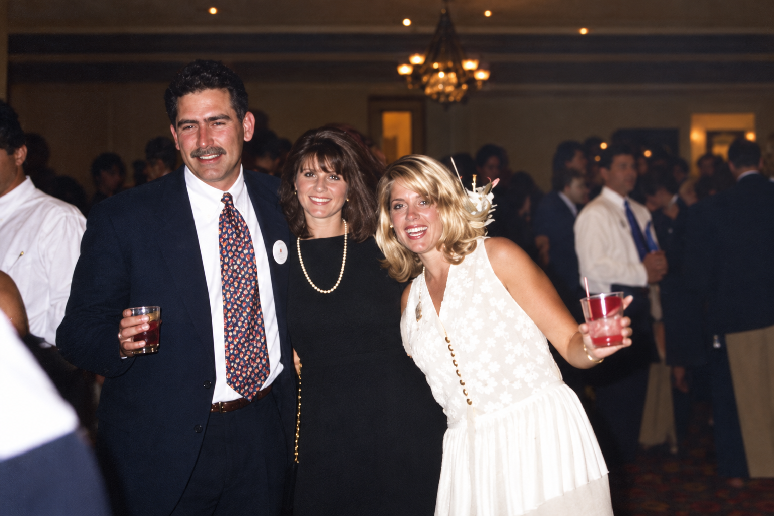 A man and two women smile together for the camera. Color interpretation.