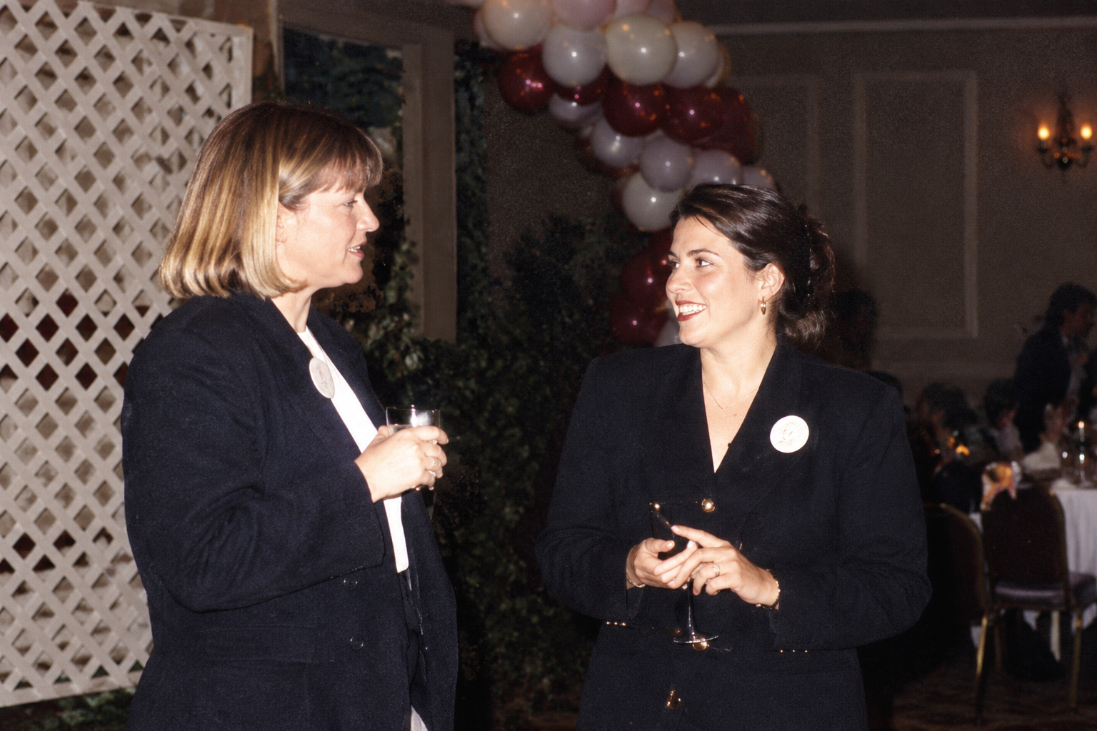 Two women converse beside the balloon display. Color interpretation.