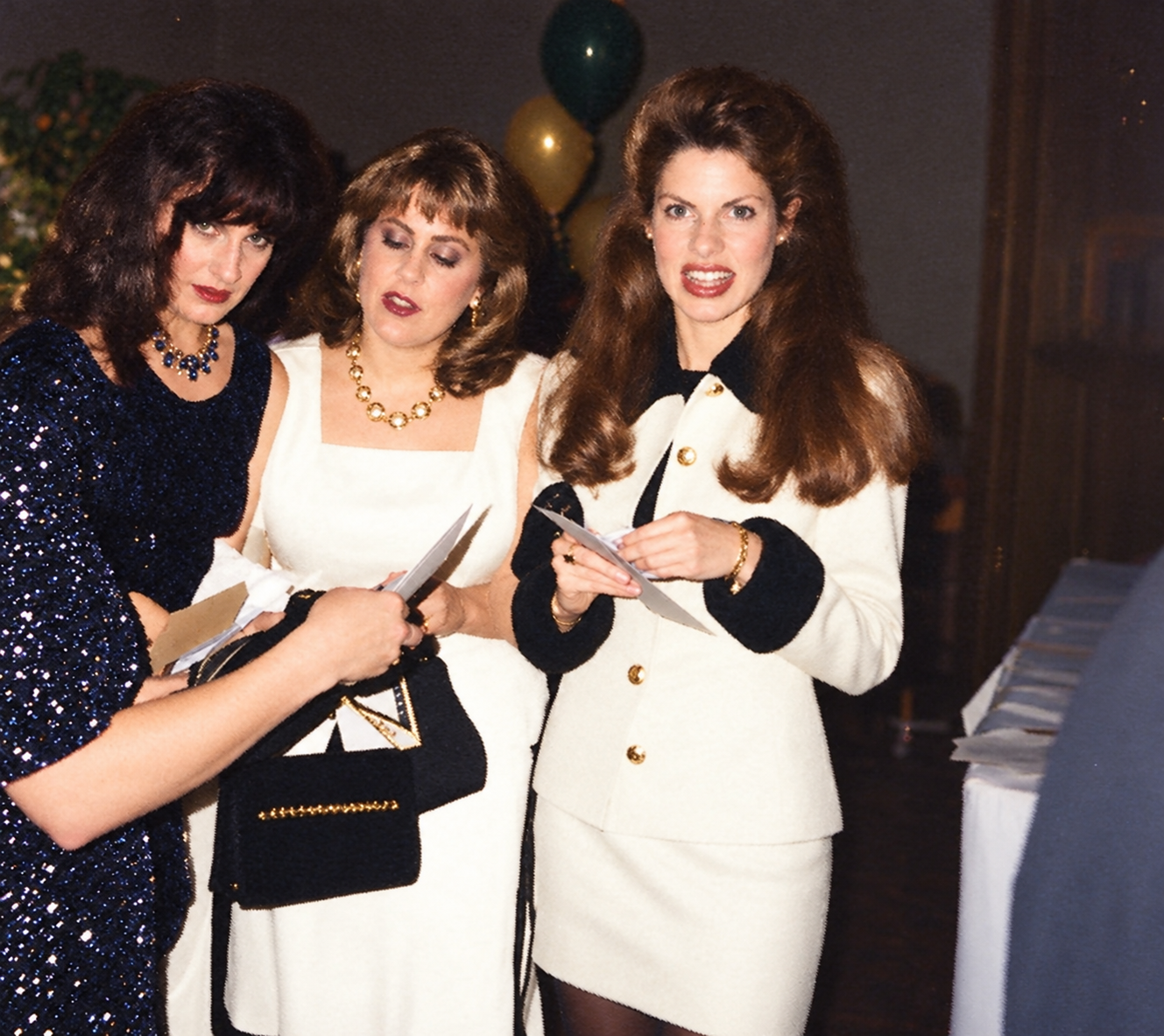 Three women smile together near the tables. Color interpretation.