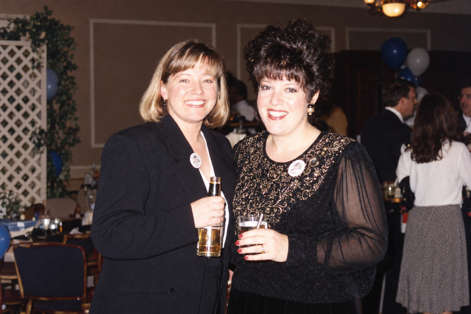 Two women smile together with drinks. Color interpretation.